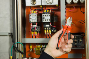 The hand of an electrician working on dangerous wires.