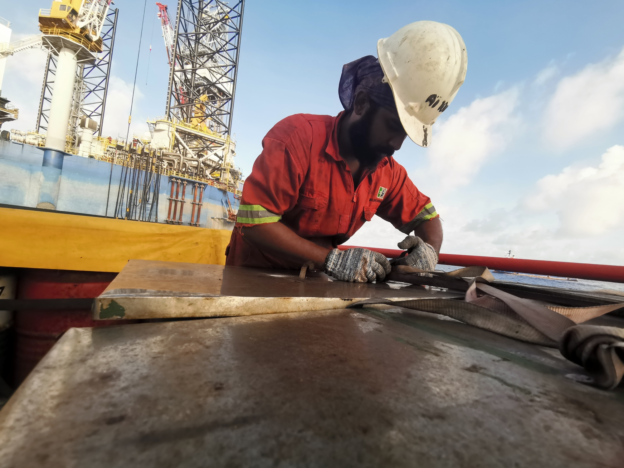 Man on sea vessel with safety jacket on conducting a job hazard analysis.