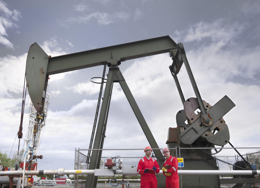 workers-standing-in-front-of-an-oil-pump